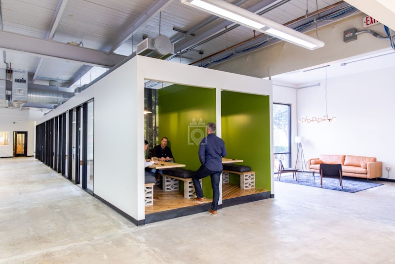 Modern private office with green accent wall, ideal for workshops and meetings.