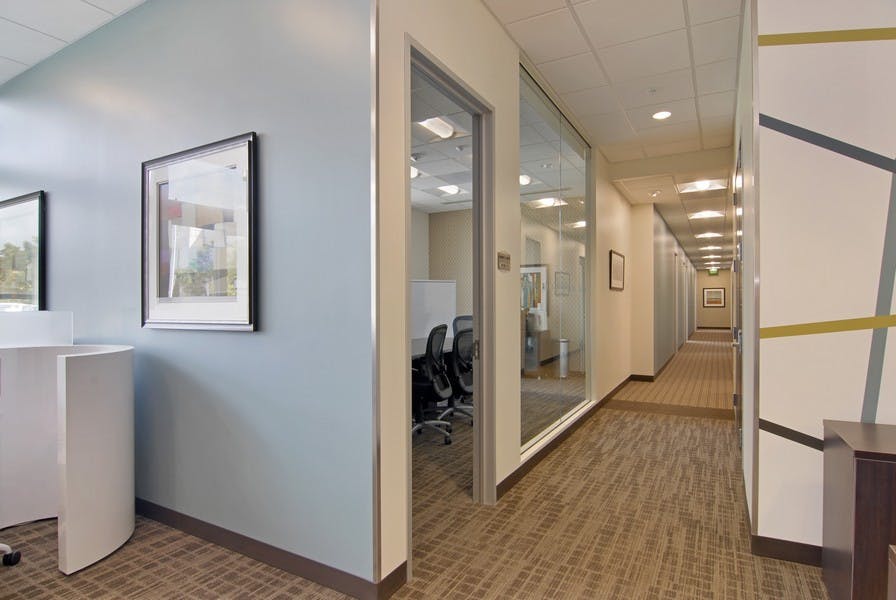 Modern office corridor with glass-walled conference room for meetings and events.