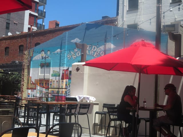Vibrant outdoor patio with colorful mural and shaded seating for social events.
