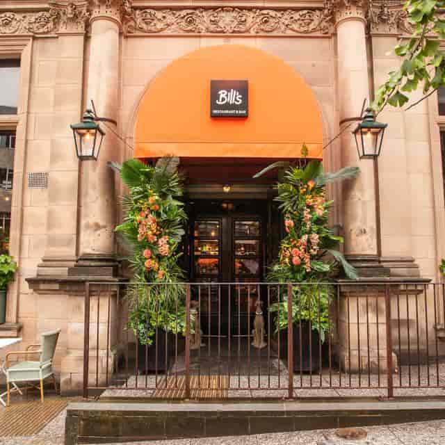 Vibrant restaurant entrance with greenery and orange awning, perfect for casual events.