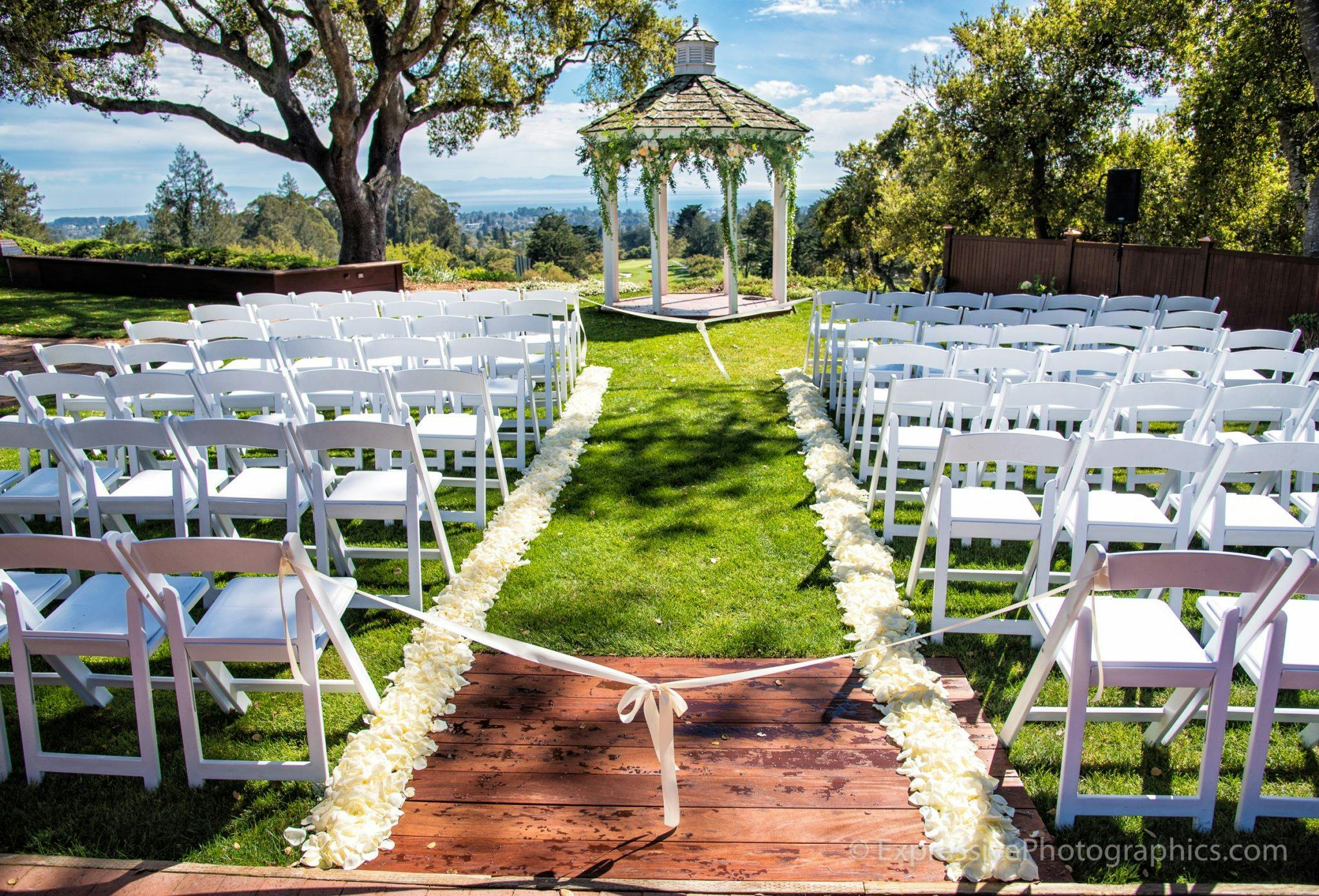 Outdoor wedding ceremony at The Hollins House with white chairs and flower petal pathway.