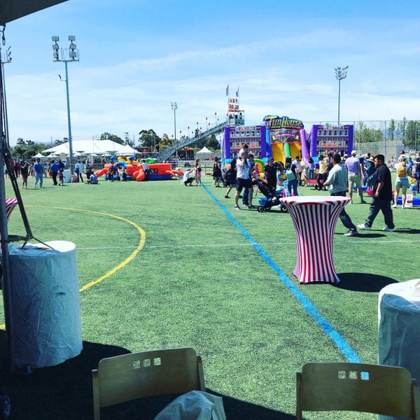 Baseball field at Twin Creeks Sports Complex, vibrant outdoor event with carnival games.