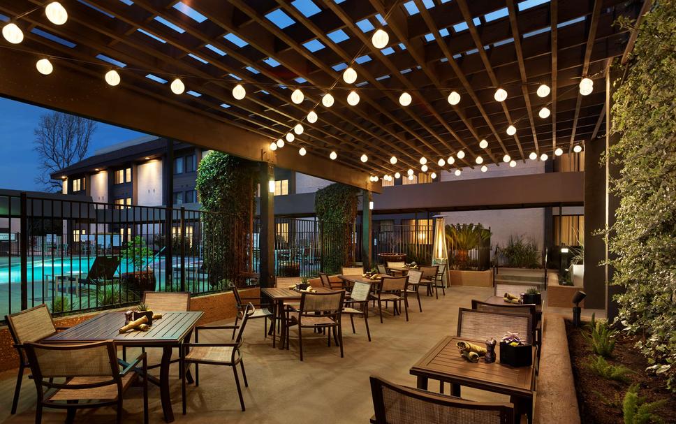 Outdoor event space at Embassy Suites Milpitas with modern furnishings and pool access.