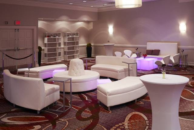 Modern lounge area with sleek white furniture for networking events at Embassy Suites.