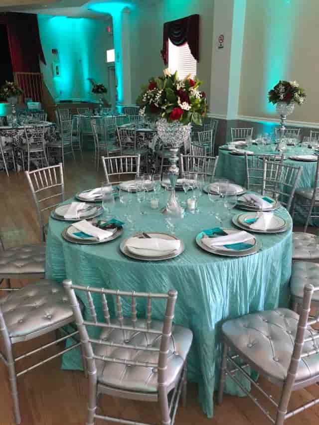 Elegant banquet hall table setting with turquoise cloth, ideal for formal events.