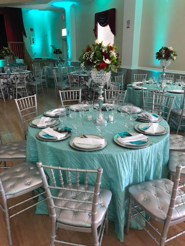 Elegant banquet hall table setting with turquoise cloth, ideal for formal events.