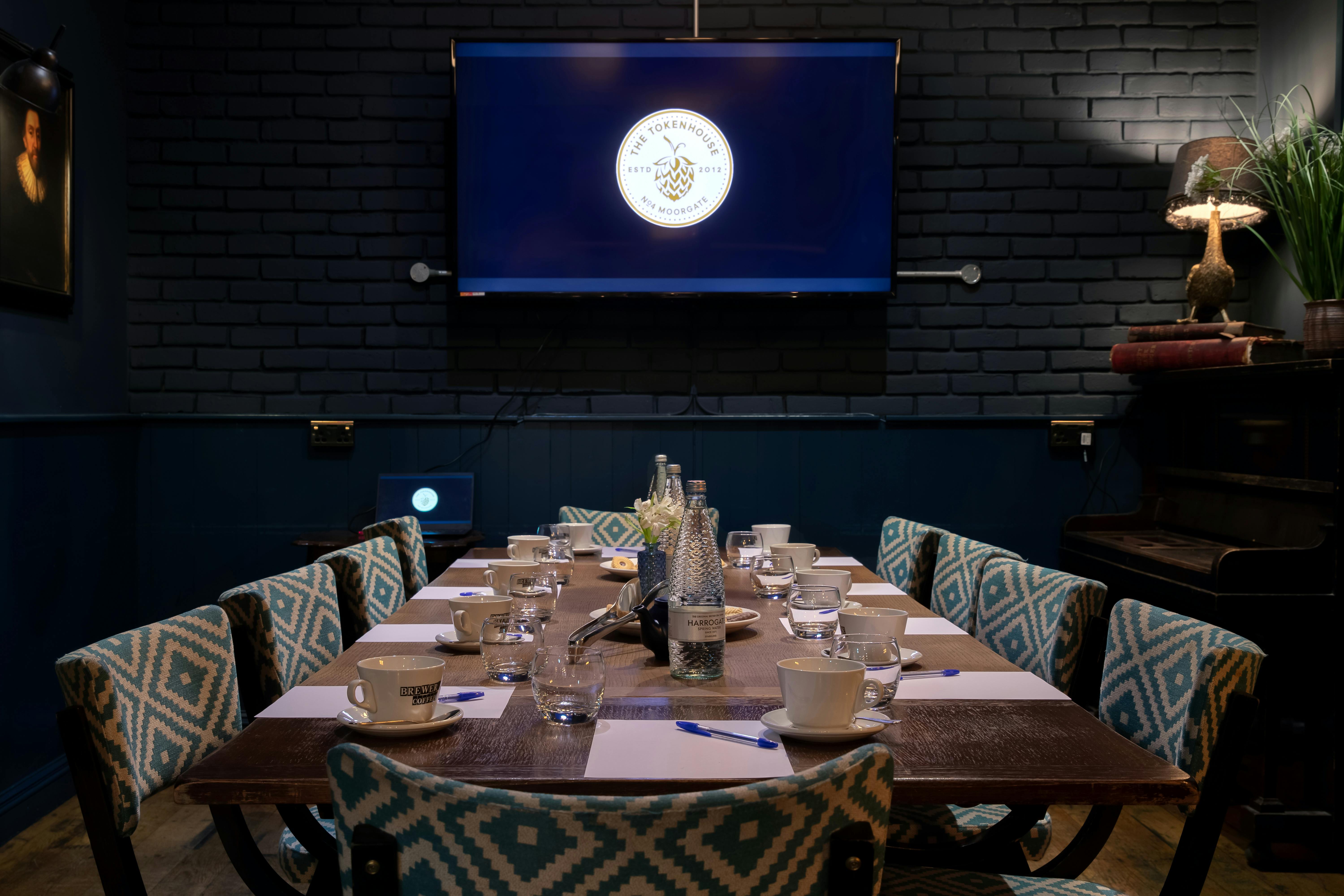 Intimate meeting room with wooden table and large screen at The Tokenhouse.