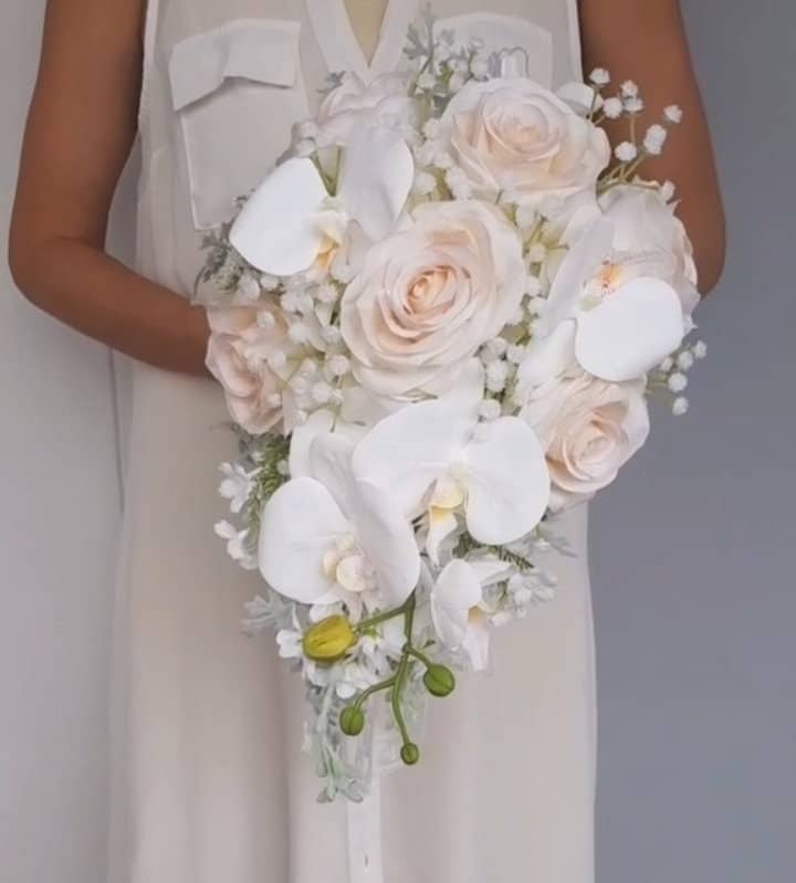 Bridal bouquet with pastel roses and white orchids for upscale weddings.