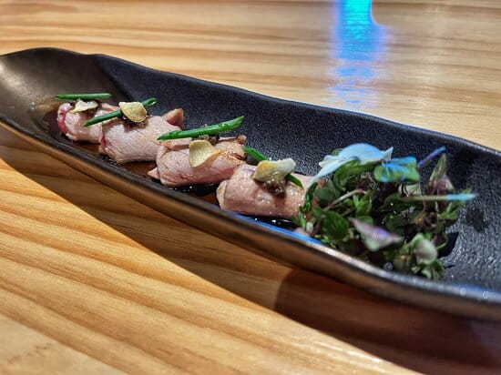 Upscale Japanese dish on sleek black plate for gourmet catering events.