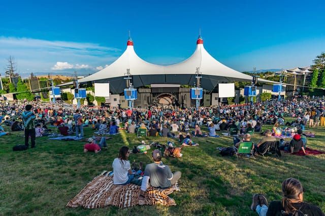 Shoreline Amphitheatre concert hall with audience under iconic tent, vibrant outdoor event.