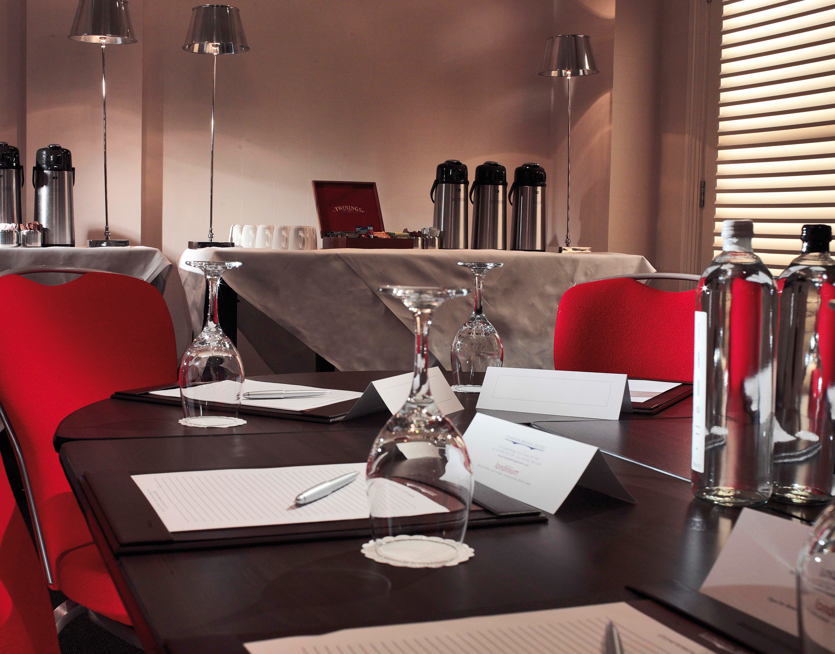 Bridge Suite at London Bridge Hotel with polished table setup for meetings and vibrant red chairs.