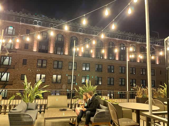 Cozy rooftop event space with string lights, perfect for networking and receptions.