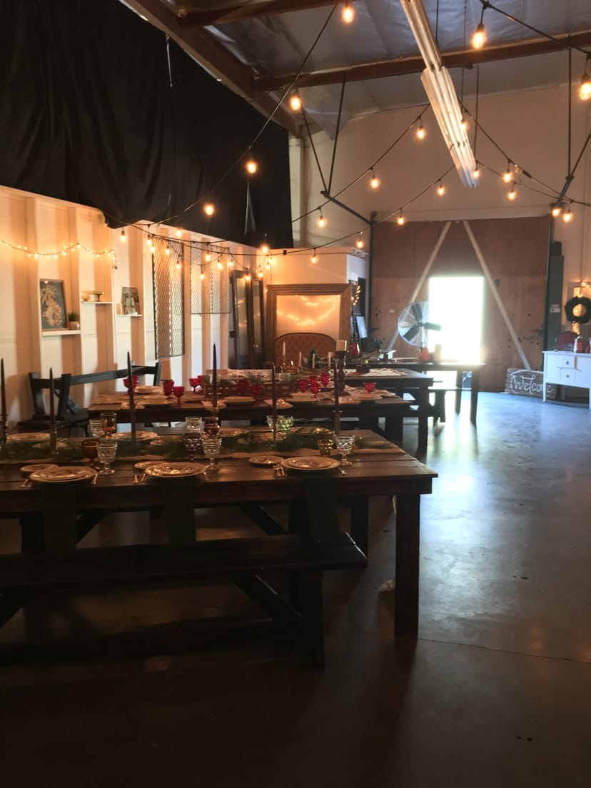 Warehouse Table in Vintage Owl Rentals, warm lighting for intimate holiday gatherings.