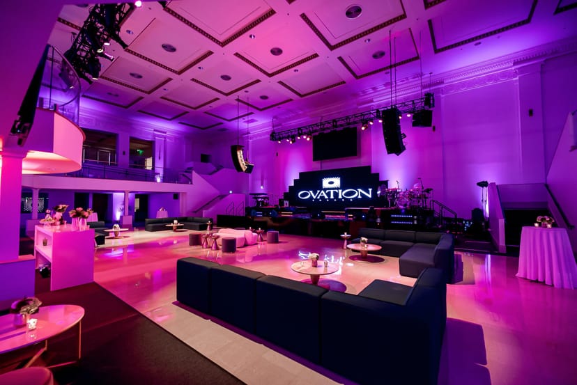 Stylish event space with lounge seating and purple lighting for corporate gatherings.