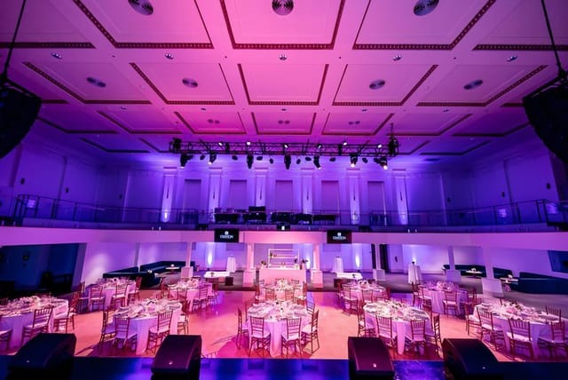 Elegant event space with round tables and purple lighting for celebrations and concerts.