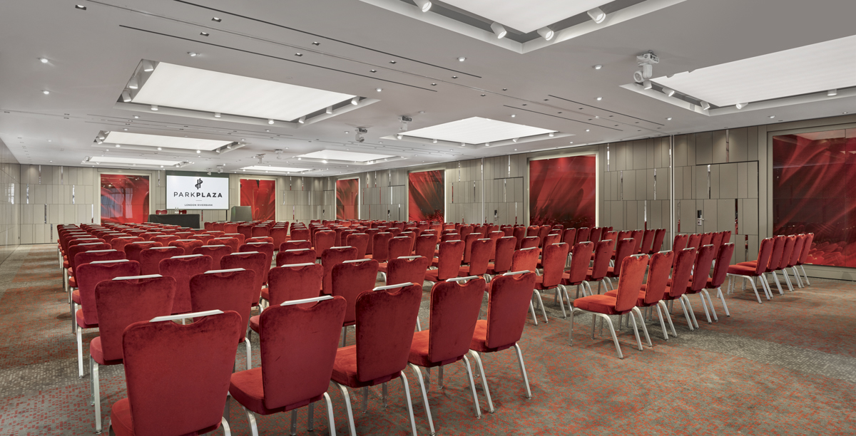 Conference room at City Suites, red chairs, ideal for seminars and events. - Banner