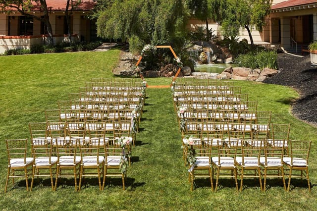 Outdoor wedding ceremony at The Bistro, Sheraton San Jose, with gold chiavari chairs.