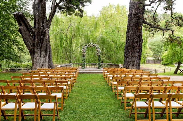 Outdoor wedding ceremony at Radonich Ranch with floral arch and wooden chairs.