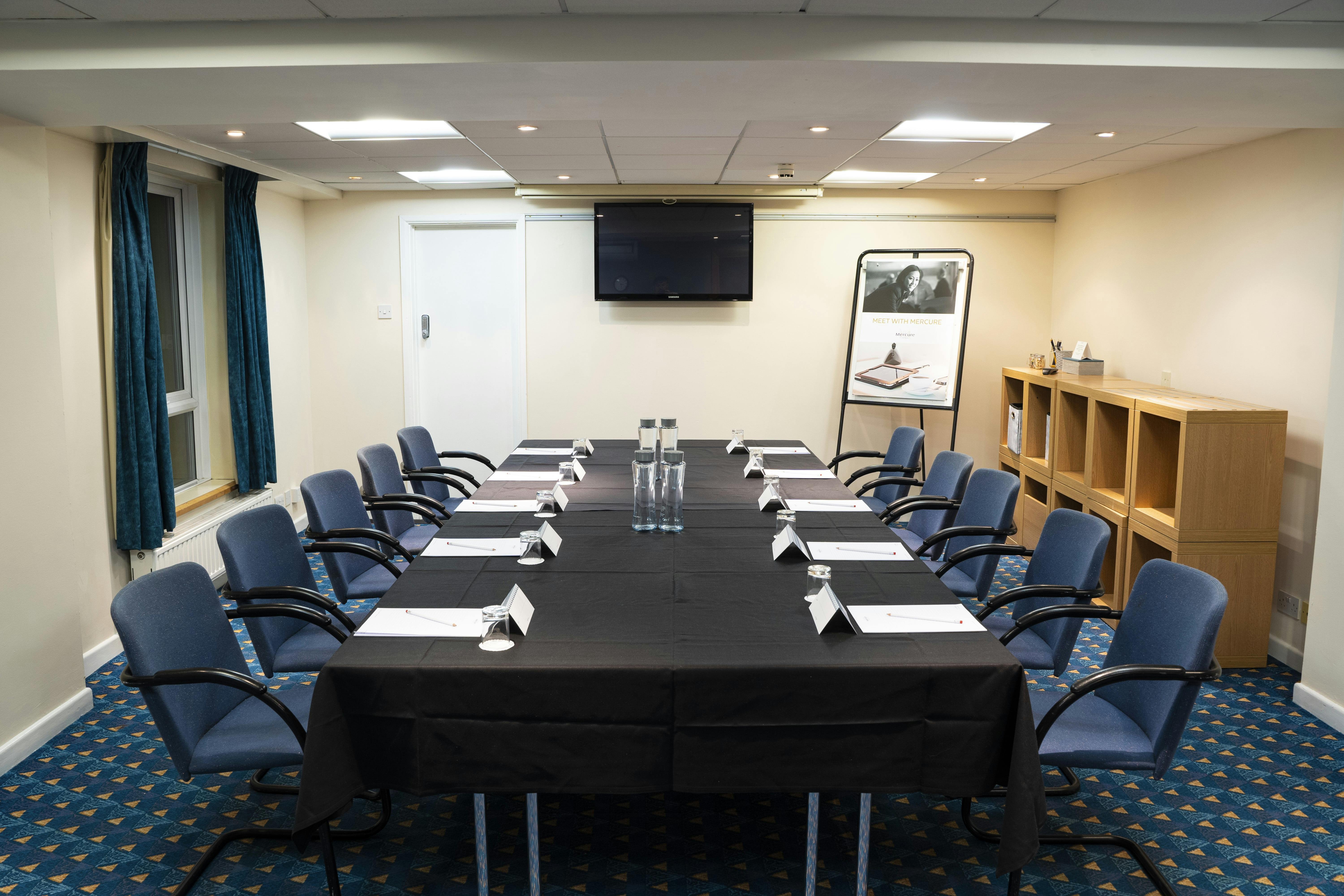 Meeting room setup at Mercure Cardiff North Hotel with bright lighting and presentation screen.