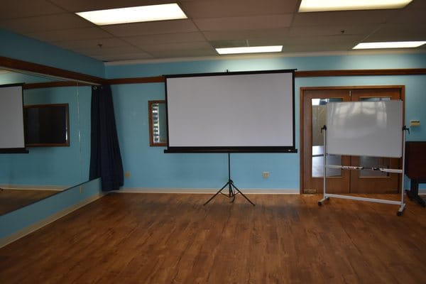 Versatile meeting room with projection screen, ideal for workshops and presentations.