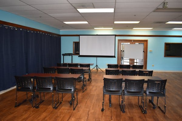 Versatile meeting space with chairs and large screen for workshops and presentations.