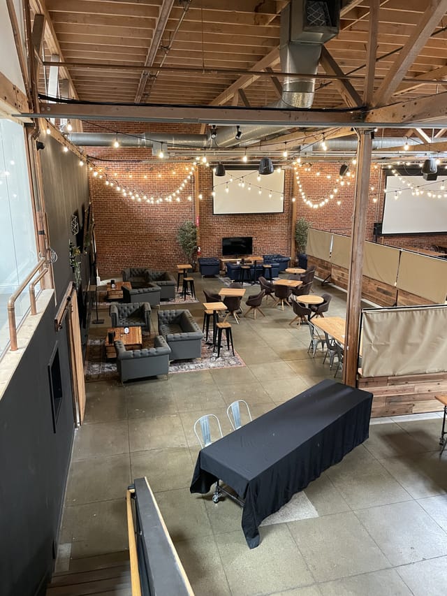 Versatile Guildhouse Event Space with warm string lights, perfect for meetings and workshops.