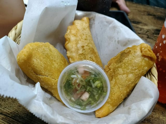 Golden empanadas with dipping sauce at Fonda Colombiana, perfect for events and networking.