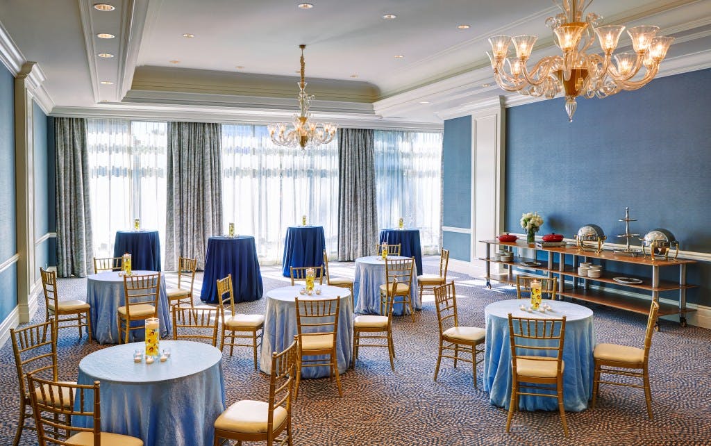 Elegant event space in Hilton San Jose with blue tablecloths and gold chairs.