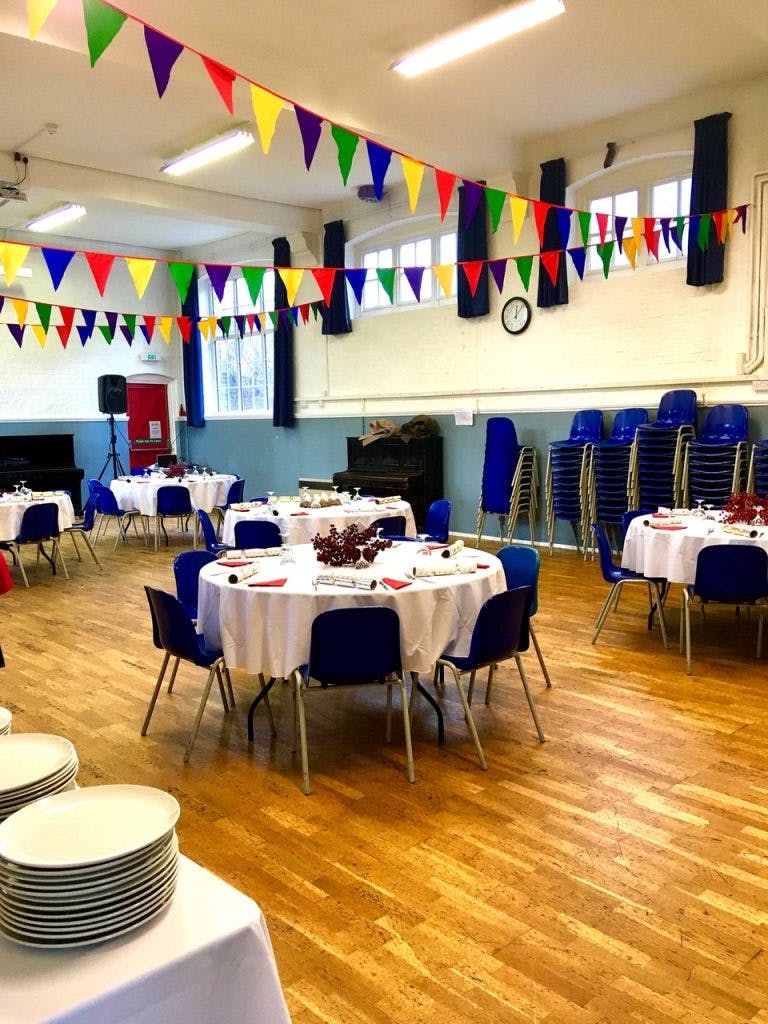 Elegant event space with round tables, blue chairs, and festive bunting in St Matthias Halls.
