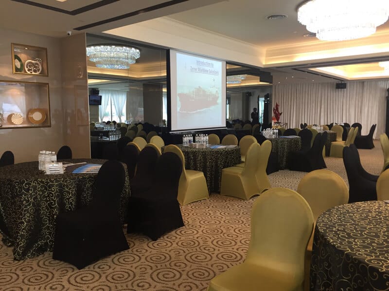 Elegant event space at Royal Palm, featuring round tables and a large presentation screen.