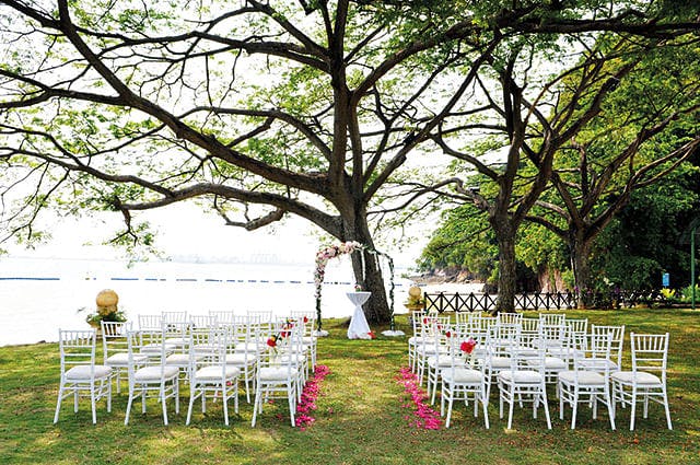 Outdoor wedding venue at Shangri-La Rasa Sentosa with white chairs and serene water backdrop.