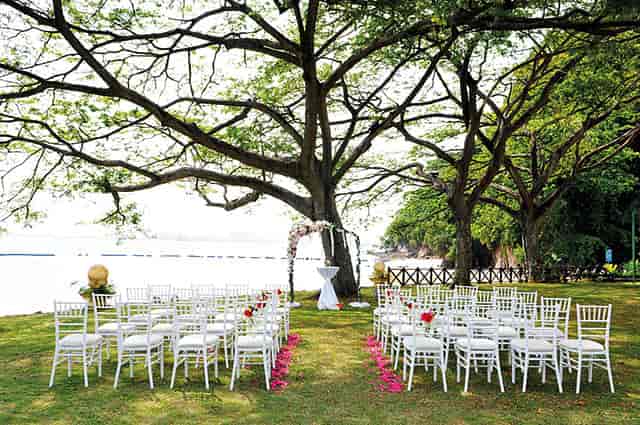 Outdoor wedding venue at Shangri-La Rasa Sentosa with white chairs and serene water backdrop.