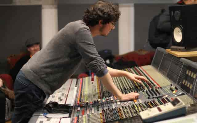 Sound engineer adjusting mixing console in Z-arts music studio for quality event audio.