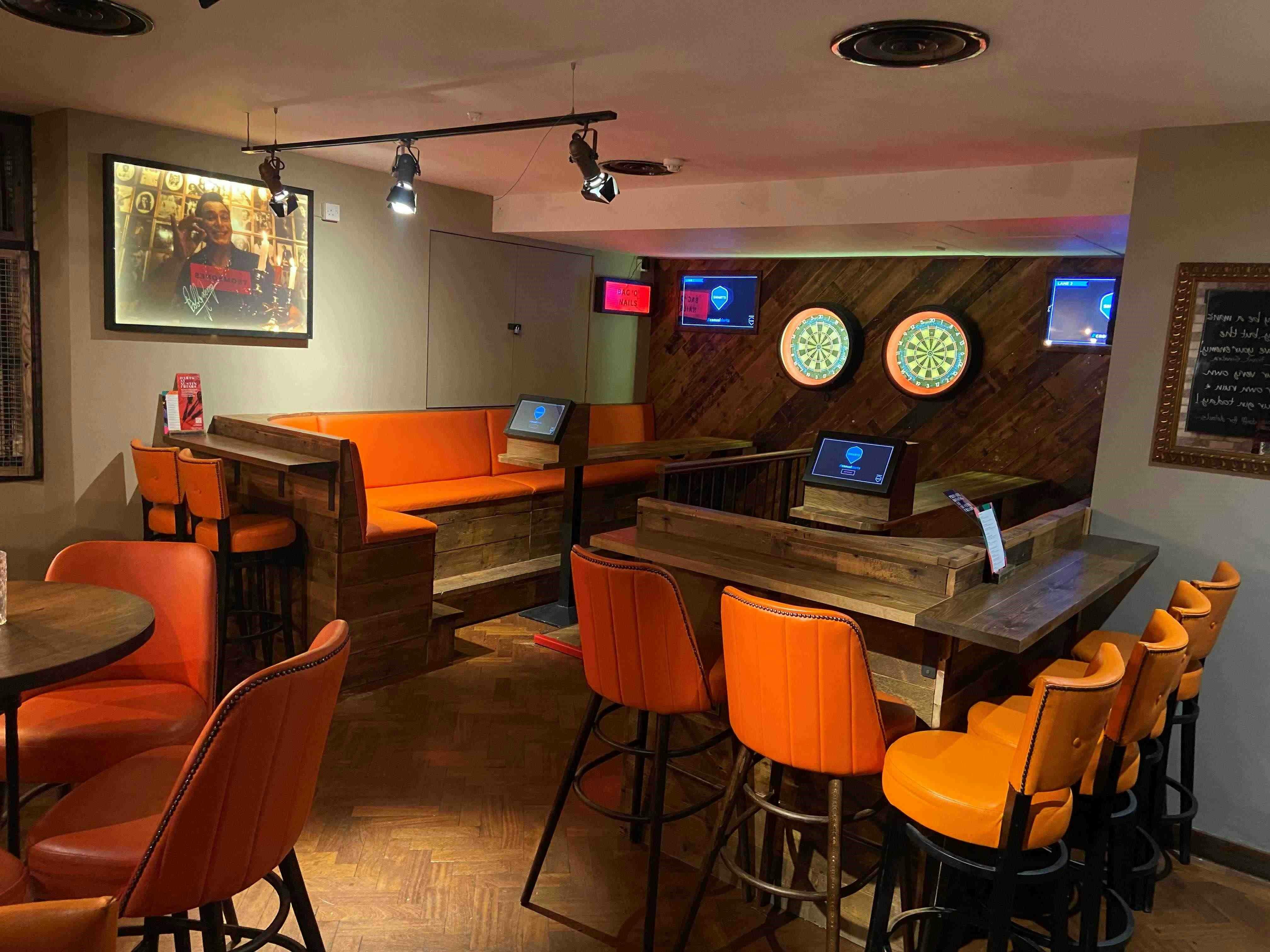 Vibrant event space with orange seating and dartboards for casual gatherings.