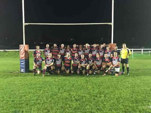 Rugby team celebrating camaraderie on Staines Rugby Club field, ideal for sports events.