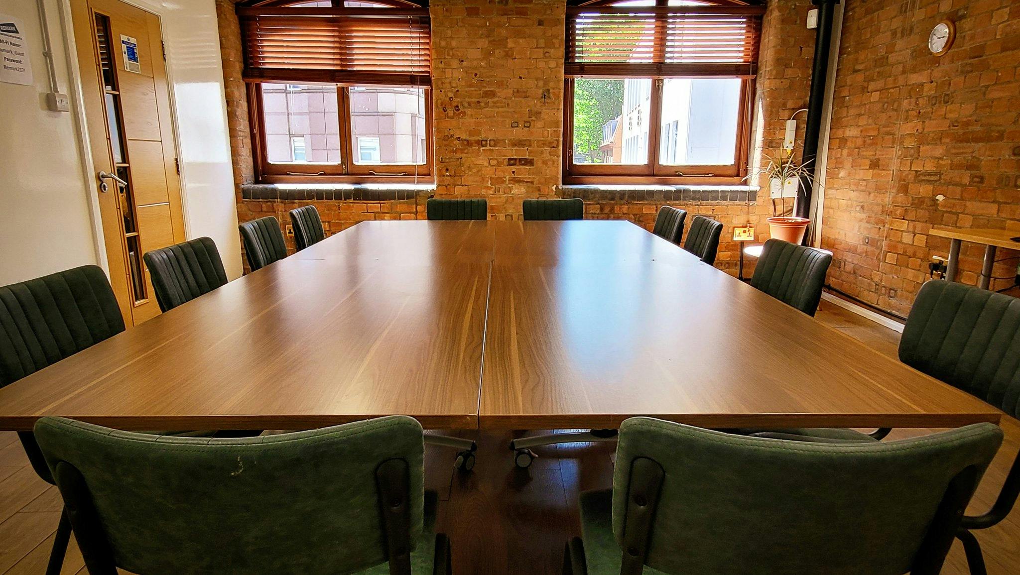 Purple Room at Remark! Events with wooden table and green chairs for meetings and brainstorming.