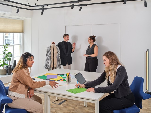 Collaborative design studio meeting with diverse team brainstorming fashion ideas.