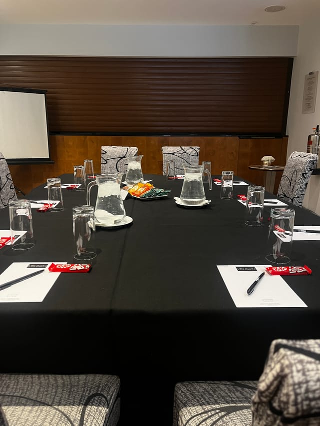 Meeting room at The Stuart Hotel with central table, water pitchers, and notepads for events.
