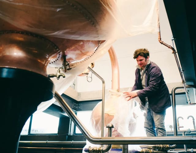 Professional preparing brewing equipment in modern Burnt Faith Brandy House for craft beer events.
