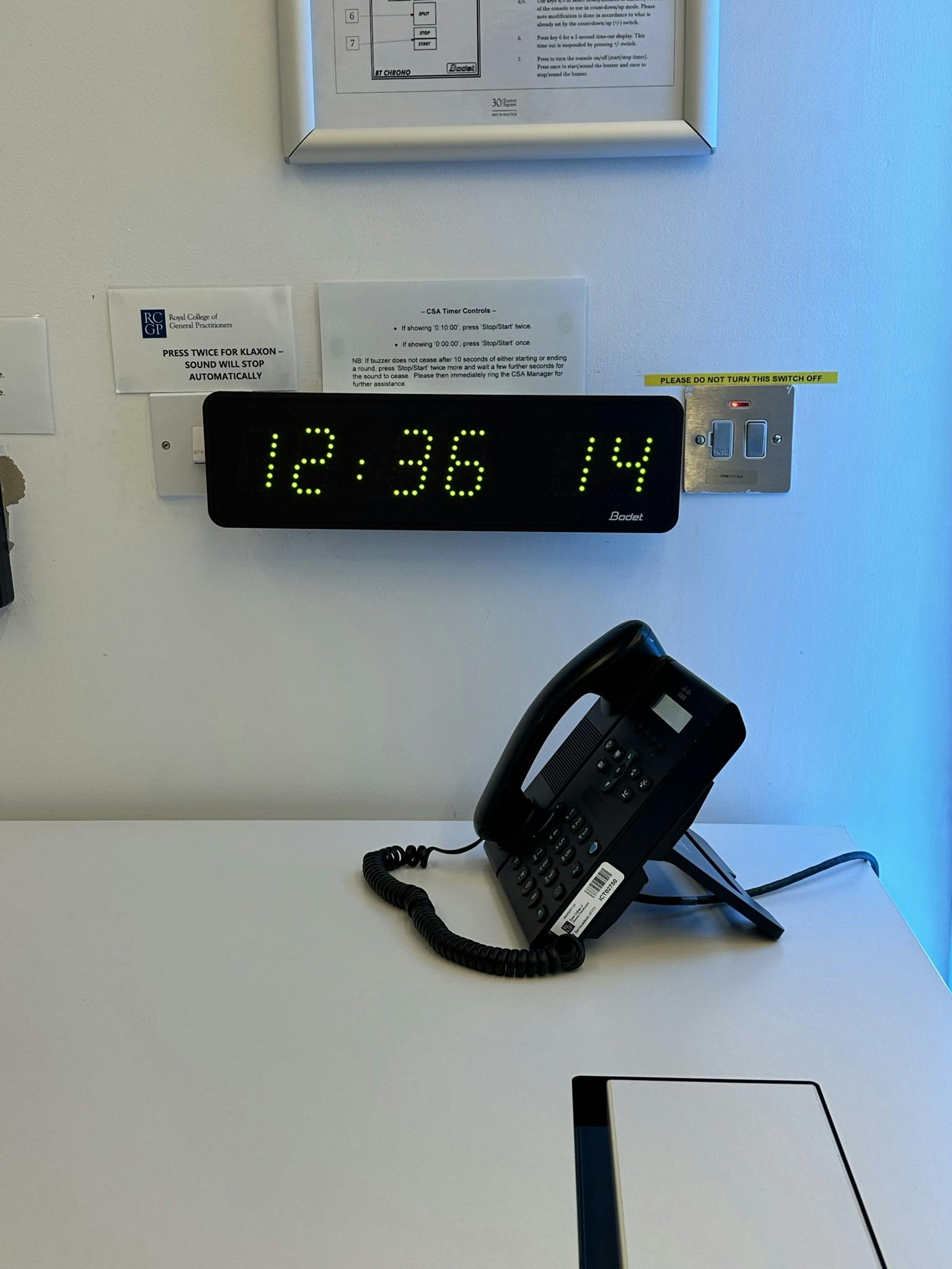 "Scenario Assessment Centre meeting room with digital clock and conference phone for events."
