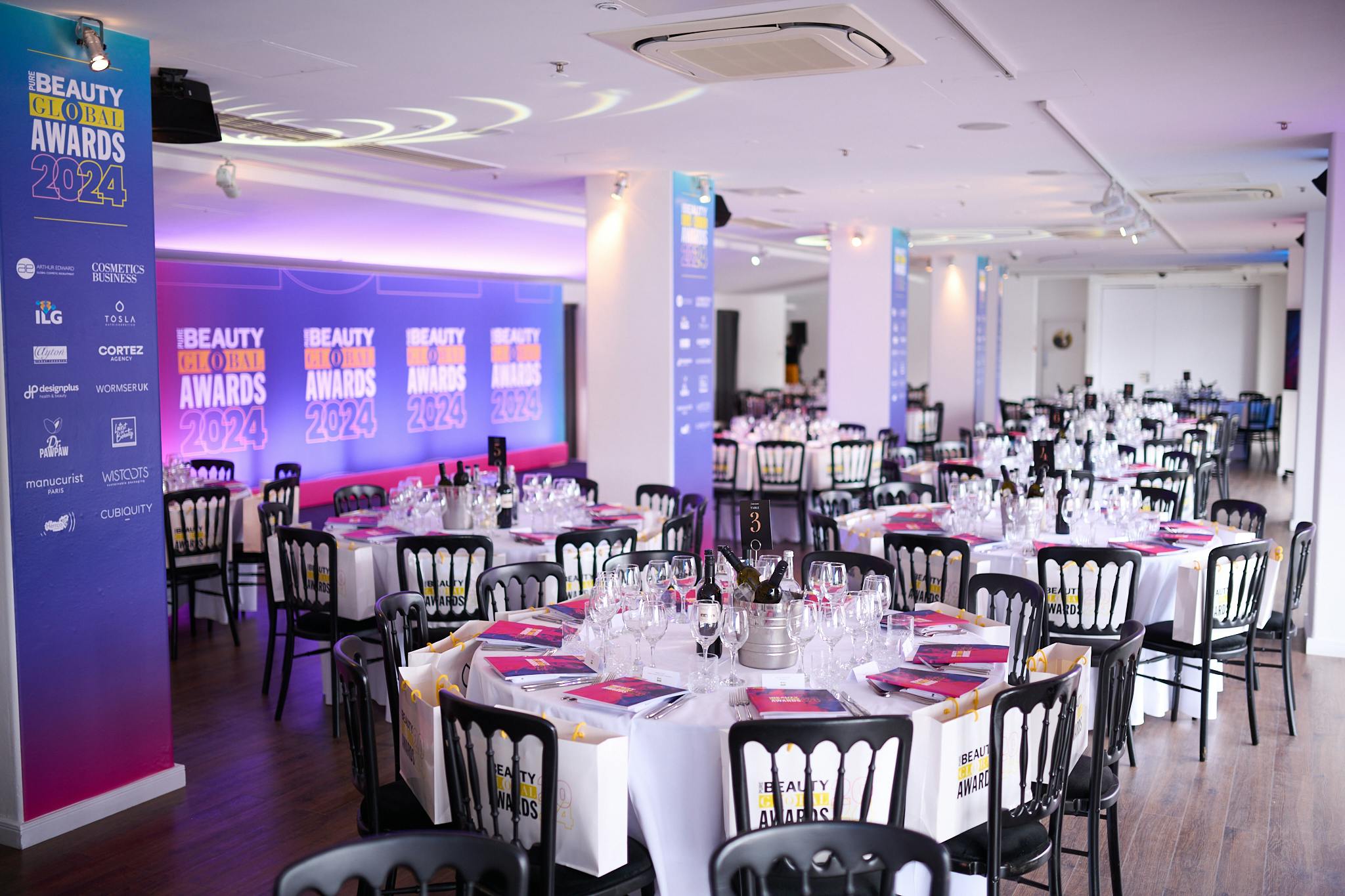 Elegant banquet setup for Beauty Awards 2024 at OXO2, featuring polished glassware and branding.