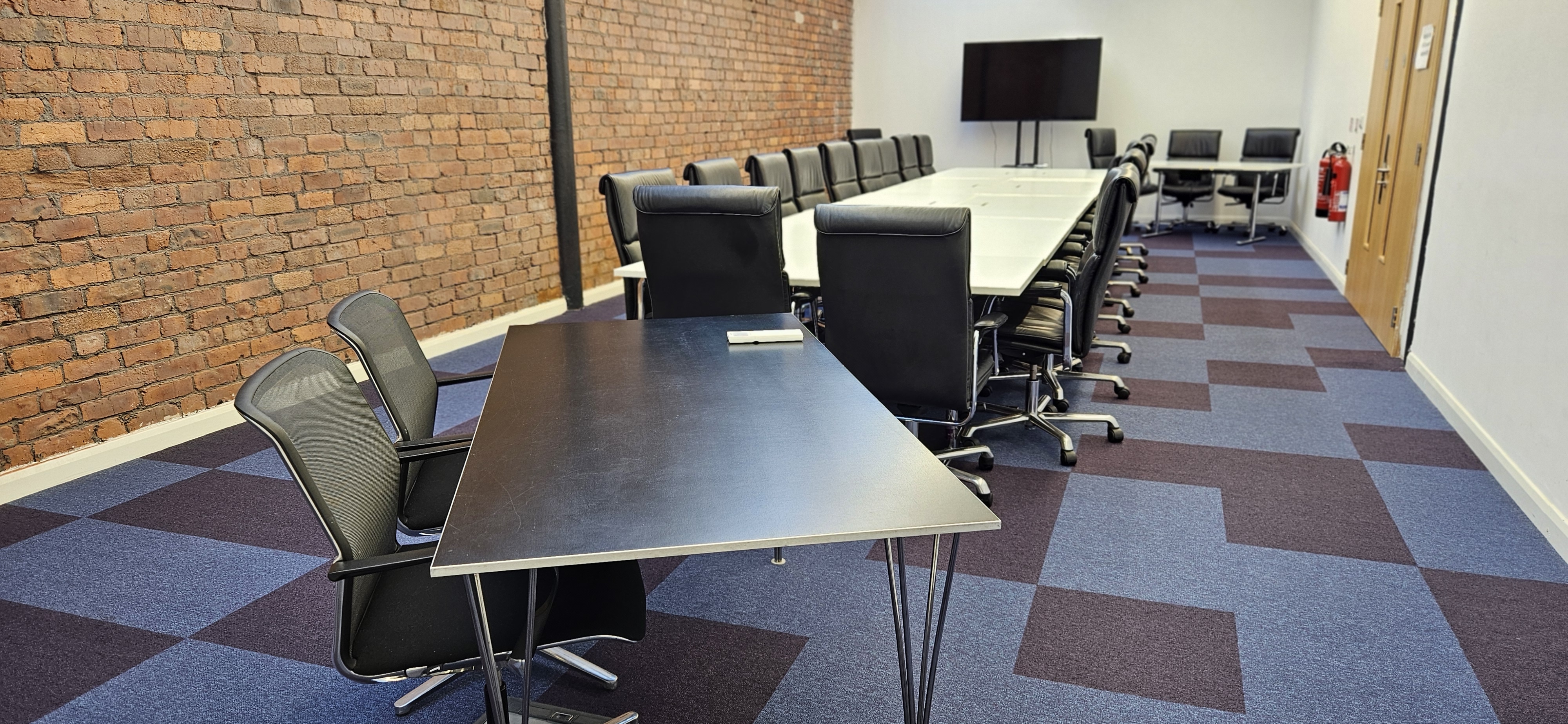 Modern meeting room at Ram Mill, featuring a long table and ergonomic chairs for workshops. - Banner