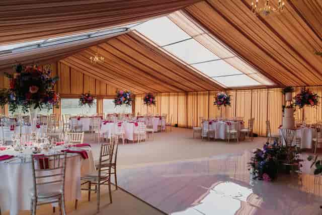 Marquee at Leeds Castle with floral decor and dance floor for luxury wedding and event hire.
