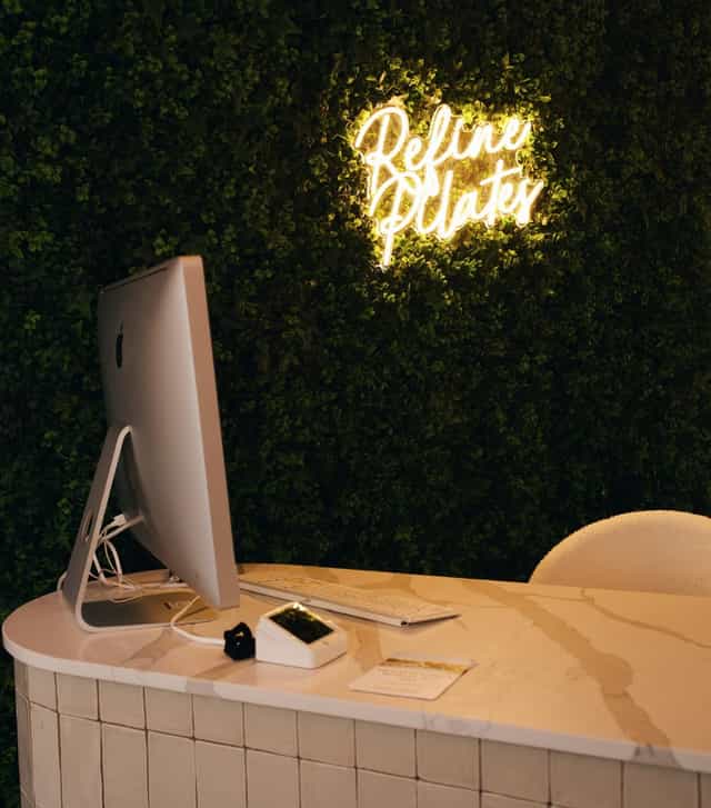 Modern event space with iMac, green wall, ideal for creative meetings and Pilates.