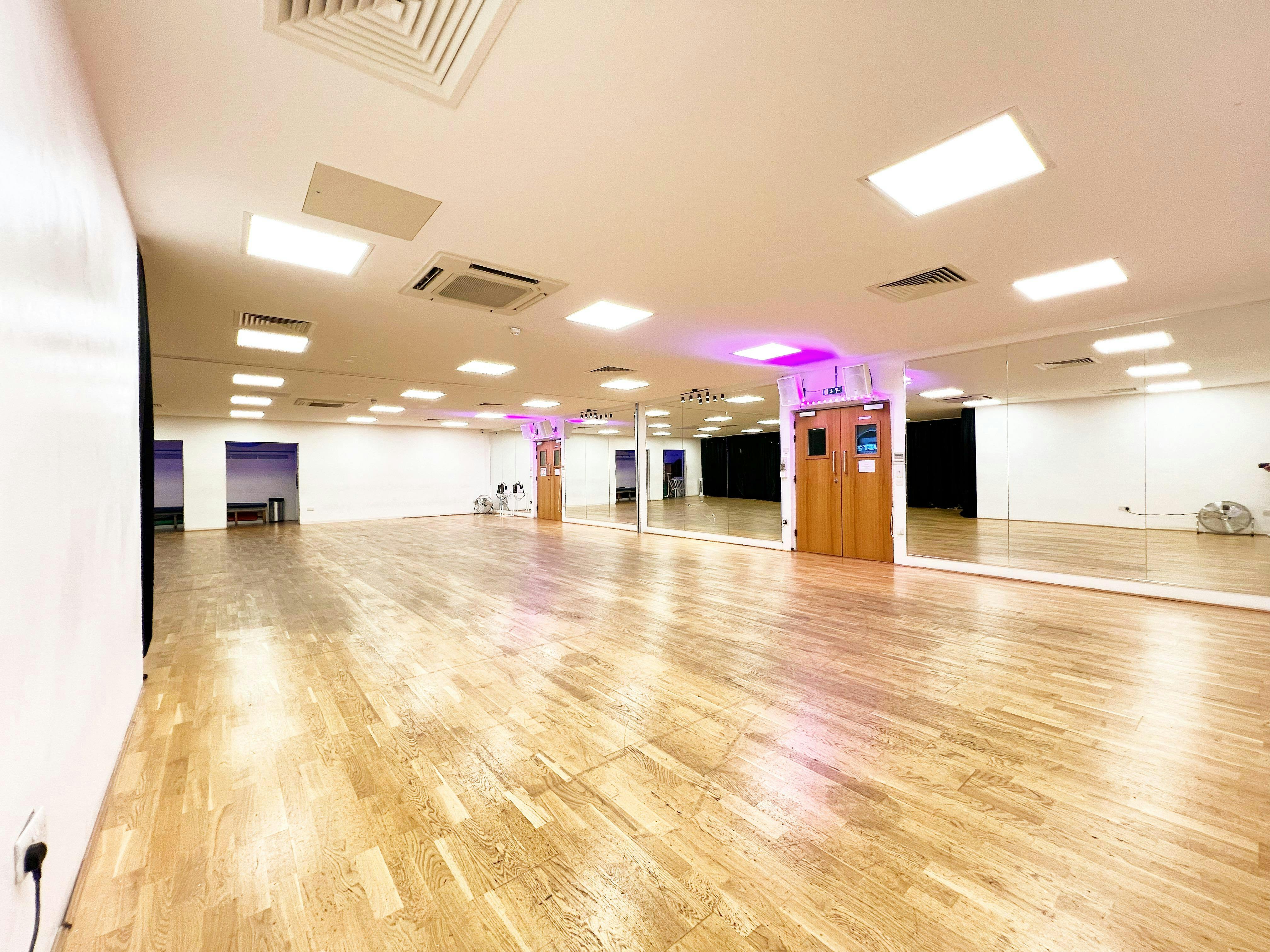 Versatile event space with polished wooden floors, ideal for workshops and fitness classes.
