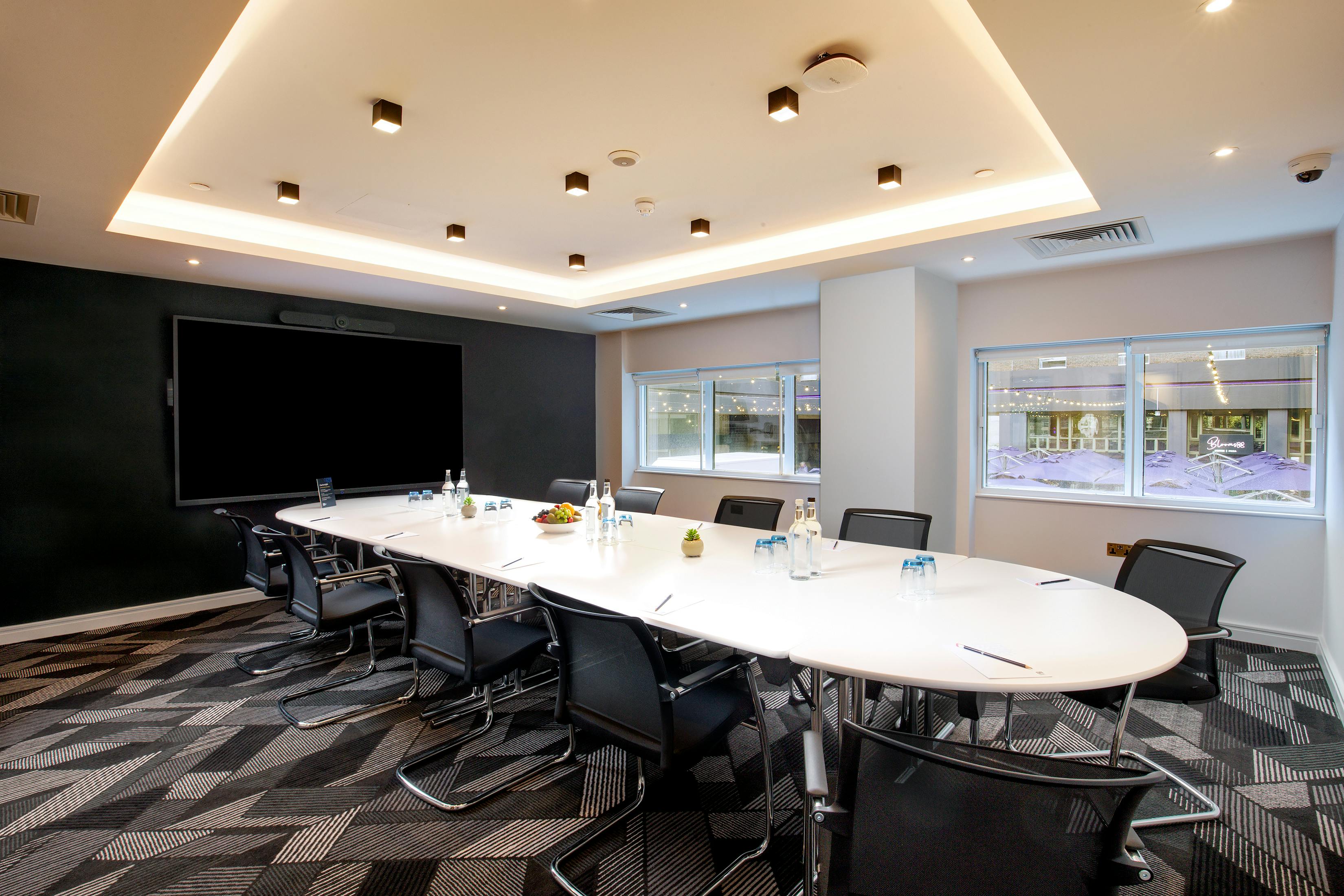 Modern meeting room at Royal National Hotel with oval table for workshops and presentations.