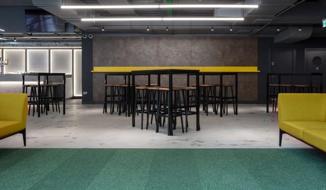 Modern Albion Bar event space with high-top tables and vibrant yellow accents.