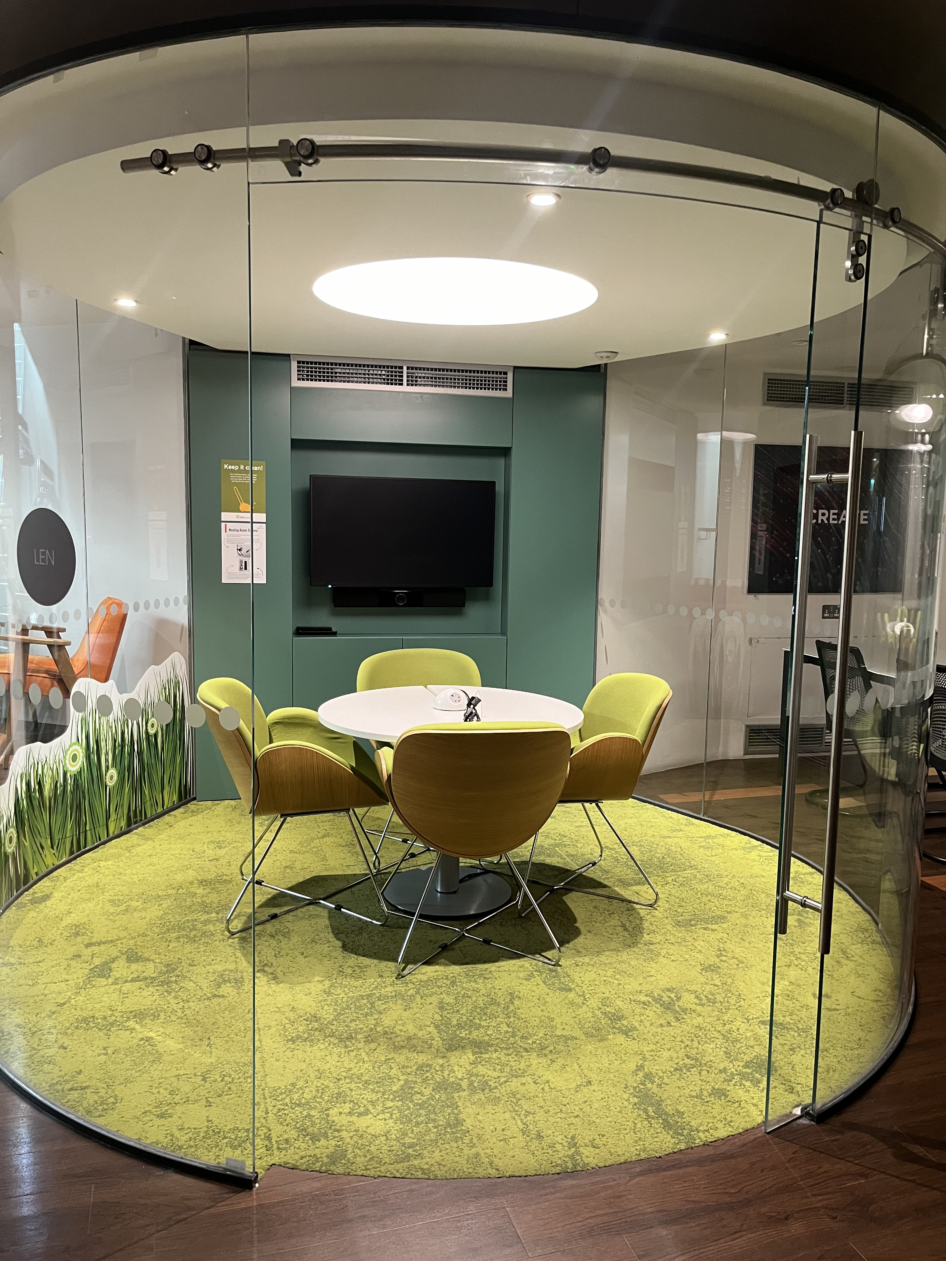 Modern meeting space with round table and vibrant seating at Pod Len, IDEALondon. - Banner