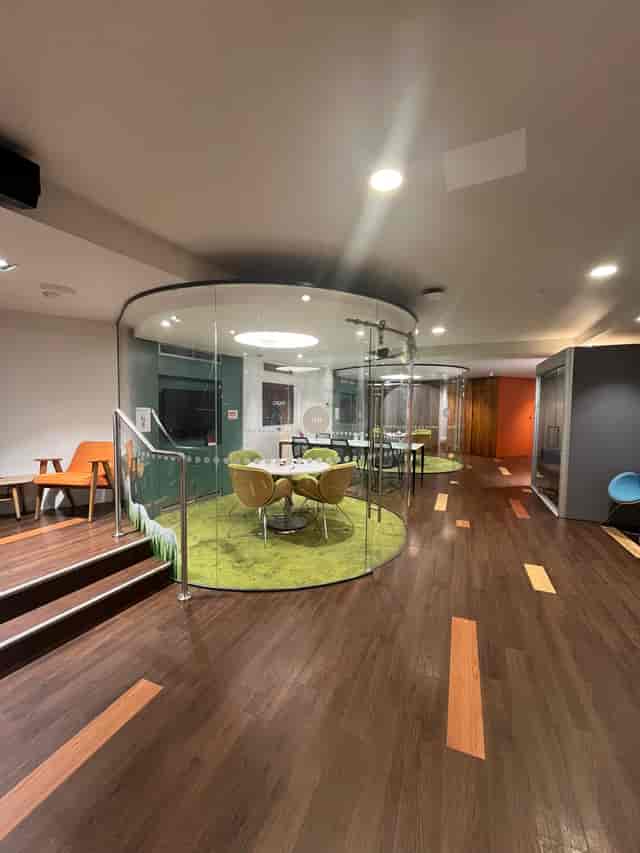 Modern meeting space with glass walls and green carpet for creative brainstorming sessions.