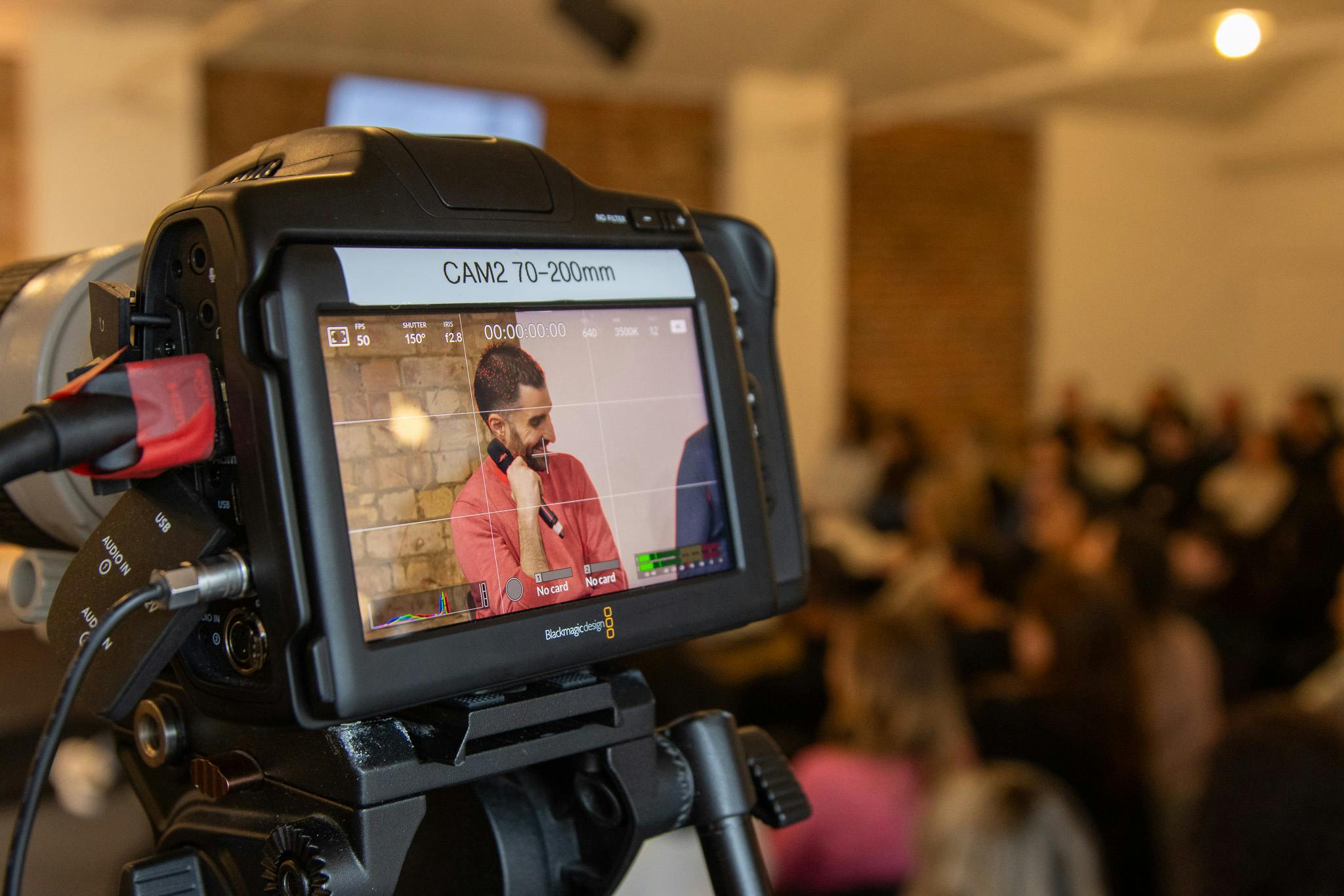 Hybrid event live streaming with a video camera capturing a speaker engaging an audience.